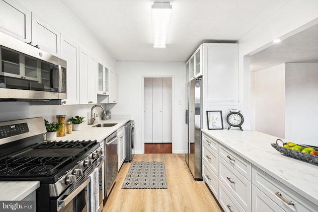 kitchen featuring light stone countertops, appliances with stainless steel finishes, white cabinetry, and sink