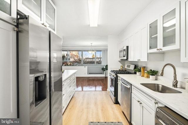 kitchen with white cabinetry, sink, stainless steel appliances, light stone counters, and light hardwood / wood-style floors