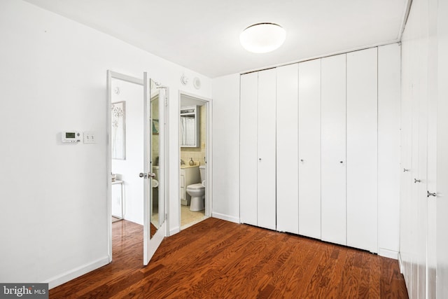 unfurnished bedroom with hardwood / wood-style flooring, a closet, and ensuite bath