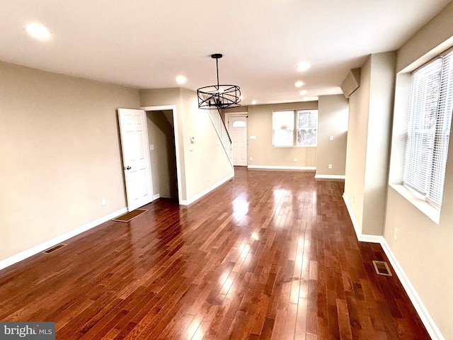 unfurnished dining area with dark wood-type flooring, a chandelier, and plenty of natural light