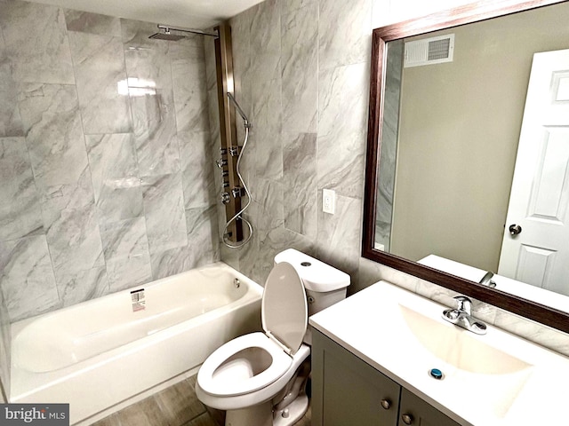 full bathroom with toilet, vanity, tile walls, and tiled shower / bath