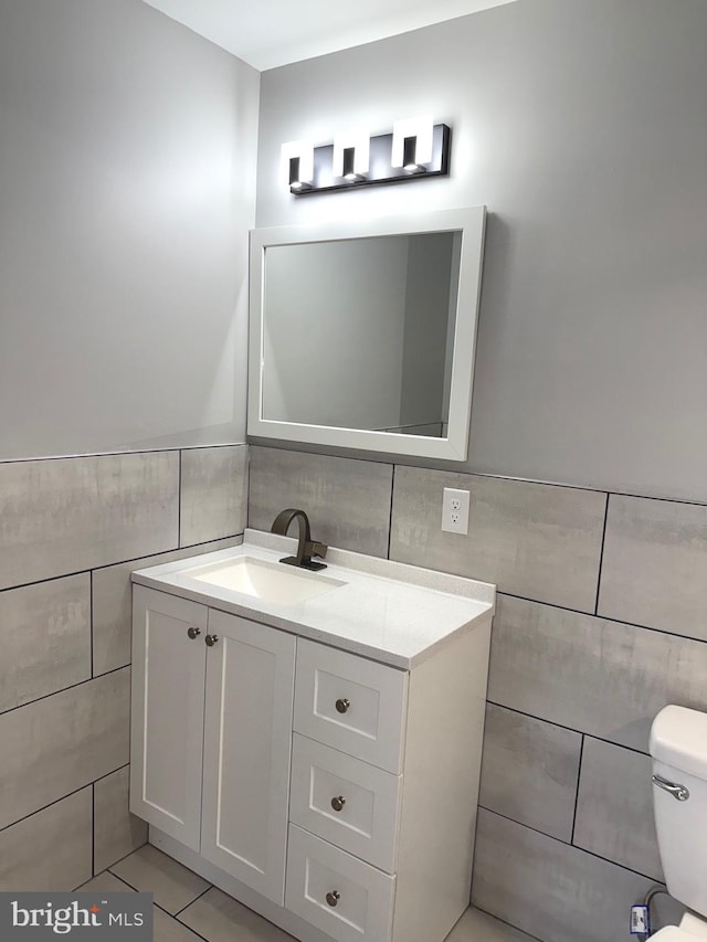 bathroom featuring vanity, toilet, and tile walls