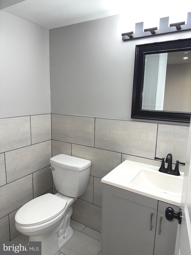 bathroom featuring vanity, tile patterned floors, tile walls, and toilet