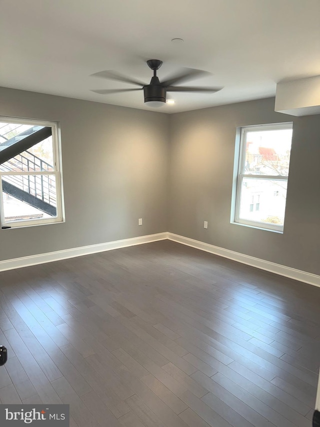 empty room featuring dark wood-type flooring, plenty of natural light, and ceiling fan