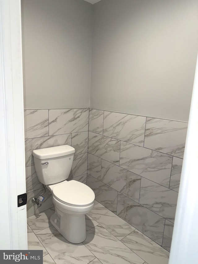 bathroom featuring tile walls and toilet