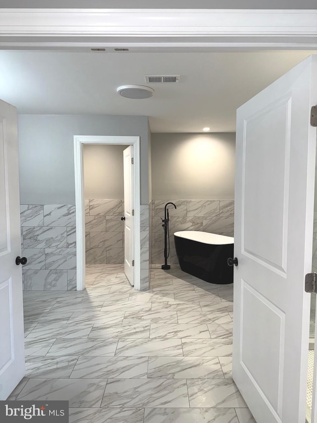 bathroom featuring a tub to relax in and tile walls