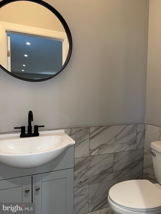 bathroom featuring vanity, tile walls, and toilet