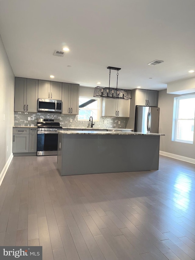 kitchen featuring tasteful backsplash, a healthy amount of sunlight, appliances with stainless steel finishes, and gray cabinetry