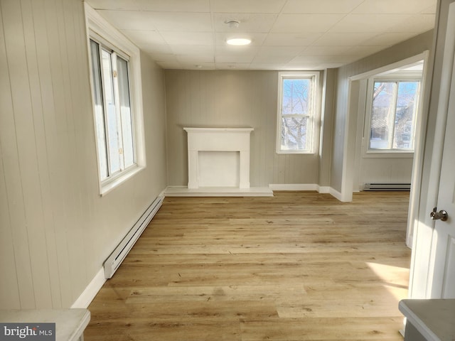 unfurnished living room with light hardwood / wood-style floors and baseboard heating