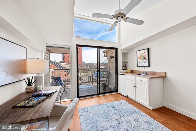 interior space with wet bar, light hardwood / wood-style floors, and ceiling fan