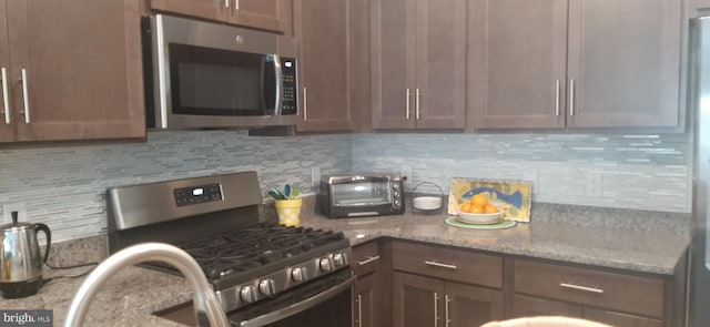 kitchen featuring decorative backsplash, stainless steel appliances, and light stone counters