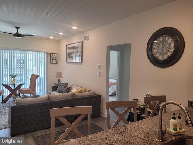 living room featuring hardwood / wood-style flooring, ceiling fan, and sink