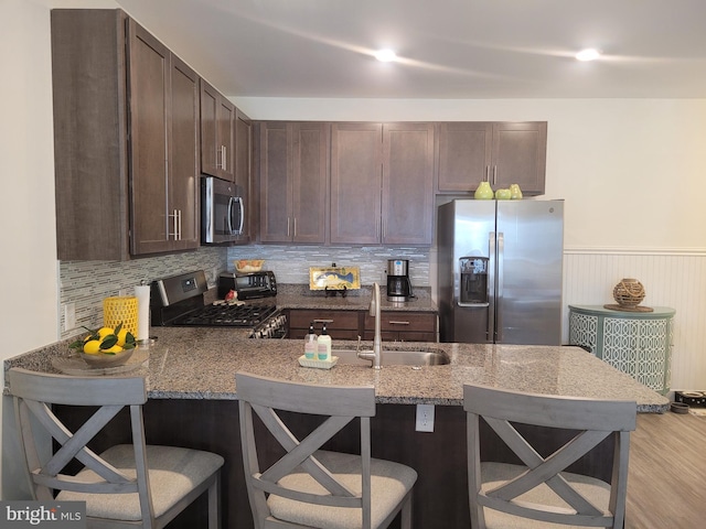 kitchen with kitchen peninsula, stainless steel appliances, a breakfast bar area, and sink