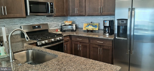 kitchen featuring decorative backsplash, appliances with stainless steel finishes, light stone counters, dark brown cabinets, and sink