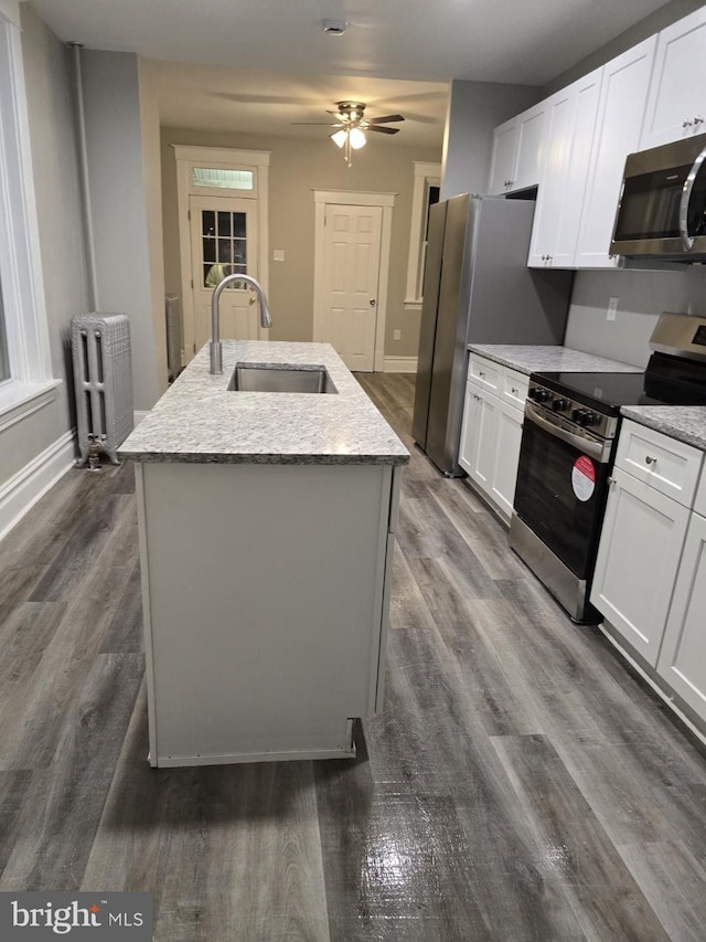 kitchen featuring white cabinetry, sink, radiator heating unit, a kitchen island with sink, and appliances with stainless steel finishes