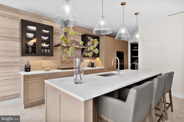 kitchen with stainless steel gas stovetop, a large island, light brown cabinetry, and sink