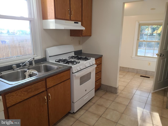 kitchen with white range with gas stovetop, light tile patterned floors, and sink