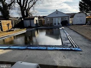 view of swimming pool with french doors and a storage shed