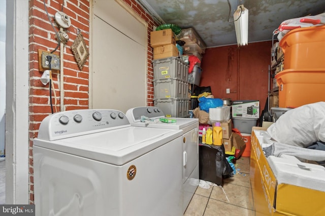 laundry room featuring brick wall, separate washer and dryer, and light tile patterned floors