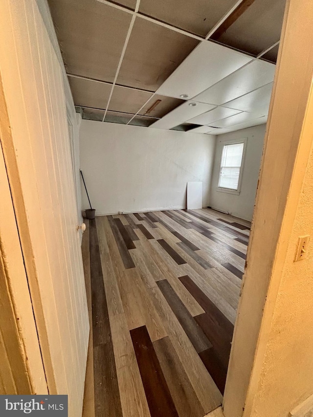 basement featuring a paneled ceiling and hardwood / wood-style floors