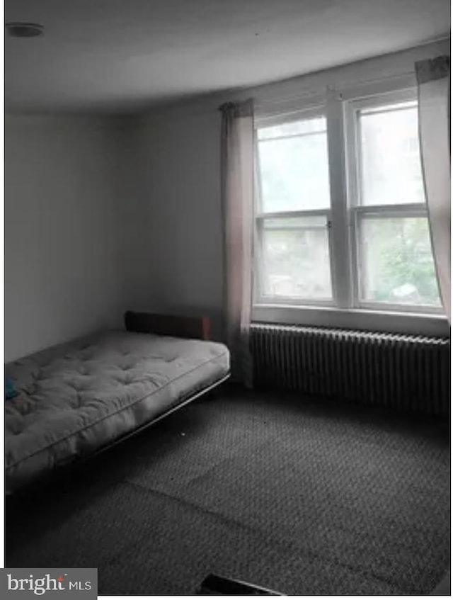 unfurnished bedroom featuring radiator and carpet floors