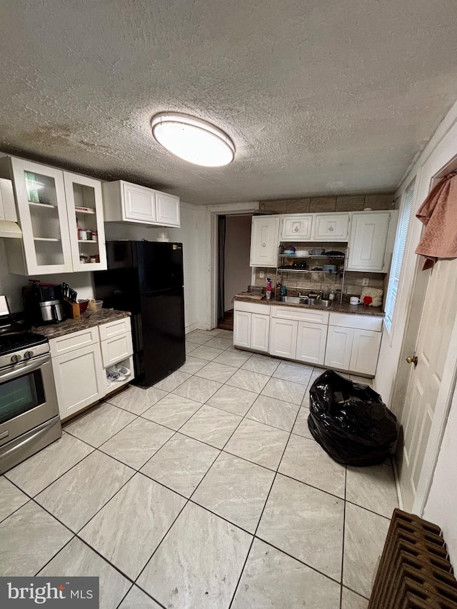 kitchen featuring white cabinets, black refrigerator, stainless steel range oven, and a textured ceiling