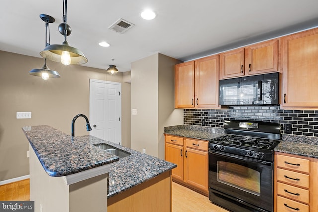 kitchen featuring black appliances, a kitchen island with sink, and light hardwood / wood-style flooring