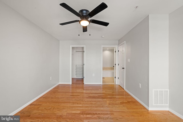 unfurnished bedroom with light hardwood / wood-style flooring, a spacious closet, and ceiling fan