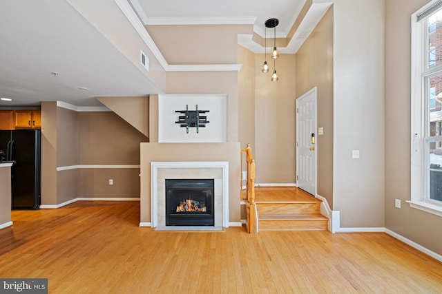 unfurnished living room with light hardwood / wood-style flooring and ornamental molding