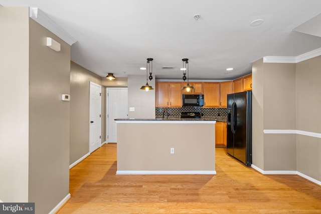 kitchen featuring a center island, black appliances, tasteful backsplash, decorative light fixtures, and light hardwood / wood-style floors