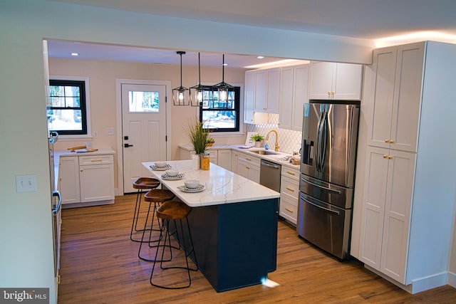 kitchen featuring sink, decorative light fixtures, white cabinetry, a kitchen island, and appliances with stainless steel finishes