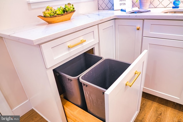 details featuring sink, white cabinets, light hardwood / wood-style floors, and light stone countertops