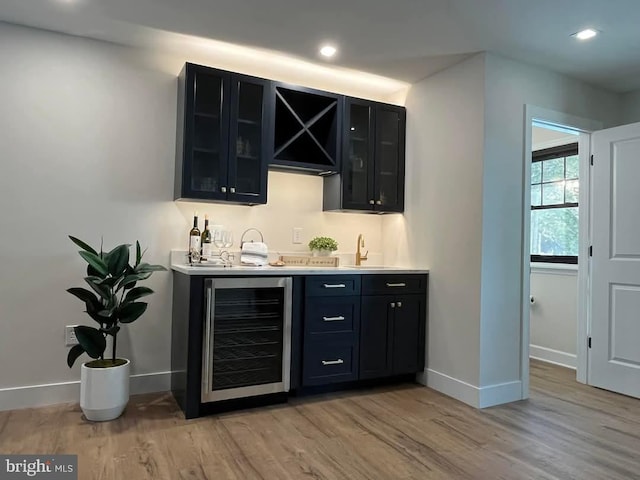 bar featuring beverage cooler, light wood-type flooring, and sink