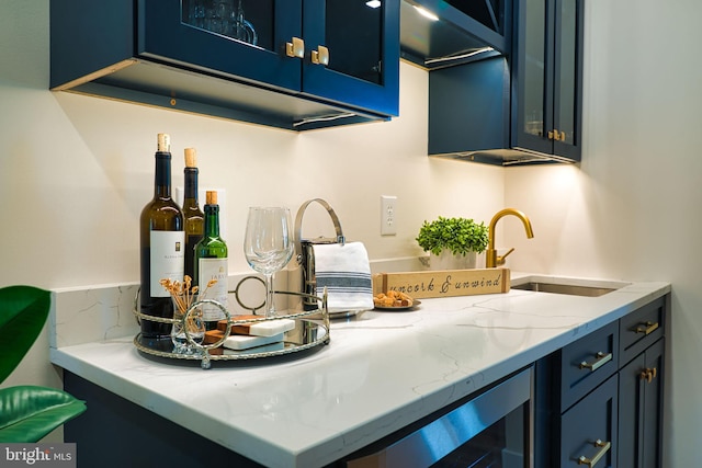 kitchen with sink, blue cabinetry, light stone counters, and wine cooler