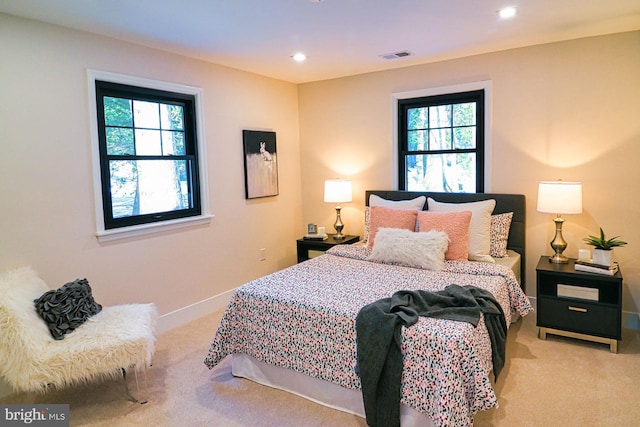 bedroom with light carpet and multiple windows