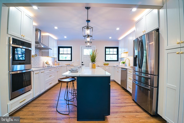 kitchen featuring white cabinets, appliances with stainless steel finishes, a kitchen island with sink, and a breakfast bar area