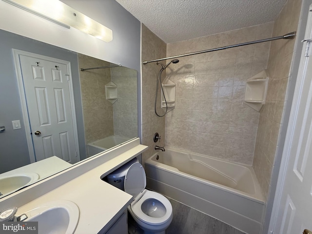 full bathroom with vanity, a textured ceiling, toilet, and tiled shower / bath