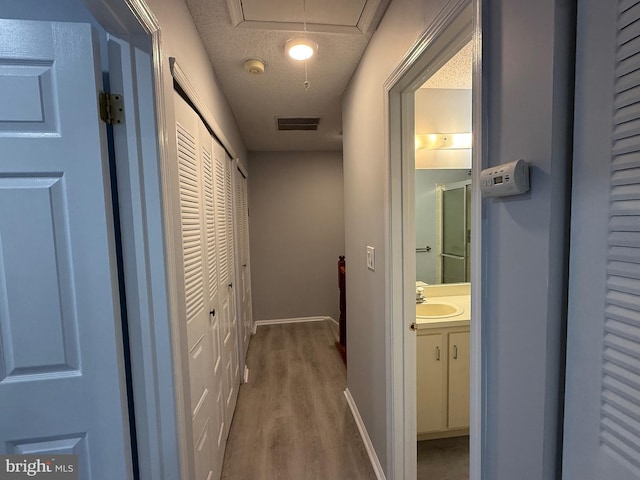 hall with wood-type flooring, a textured ceiling, and sink