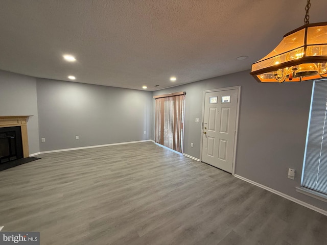 unfurnished living room with wood-type flooring and a textured ceiling