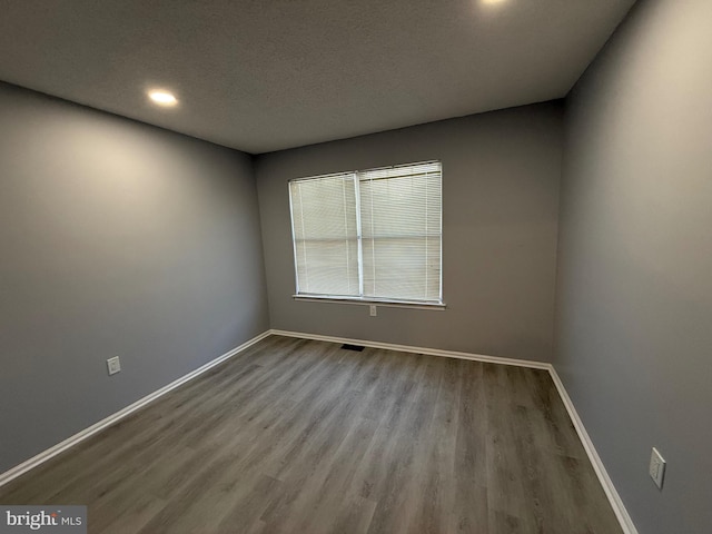 spare room with a textured ceiling and light wood-type flooring