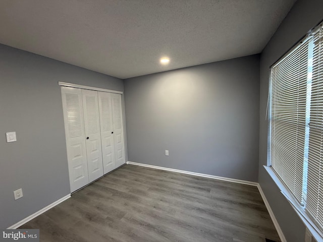 unfurnished bedroom with wood-type flooring, a textured ceiling, and a closet