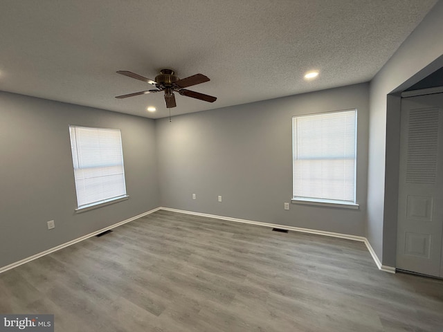 empty room with ceiling fan, light hardwood / wood-style floors, and a textured ceiling