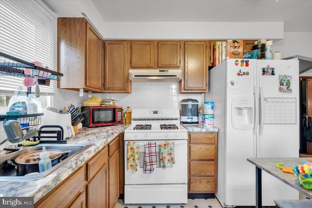 kitchen featuring tasteful backsplash, light stone counters, sink, and white appliances