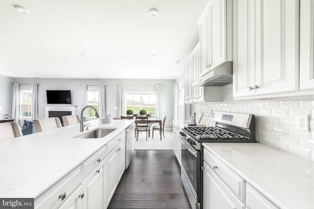 kitchen featuring light stone countertops, white cabinetry, sink, stainless steel appliances, and decorative backsplash