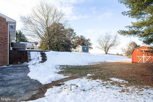 yard layered in snow featuring a storage unit