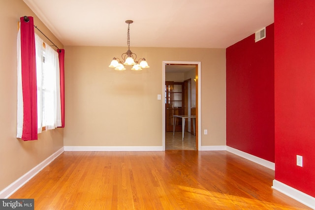 unfurnished room featuring a chandelier and hardwood / wood-style floors