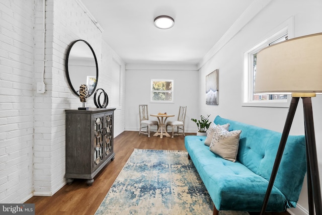 sitting room featuring hardwood / wood-style flooring, brick wall, and crown molding