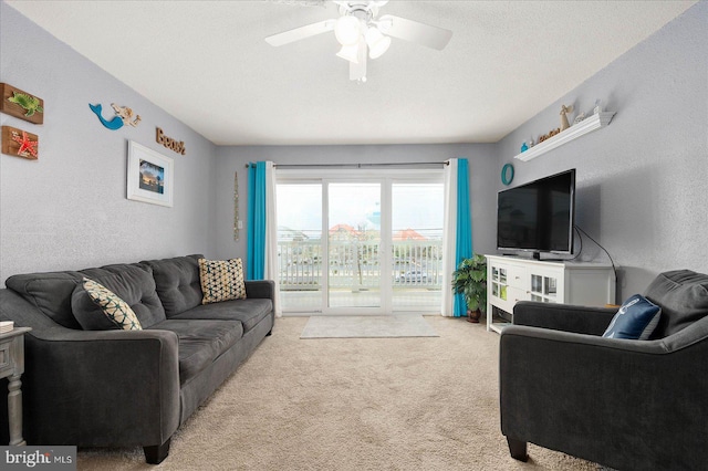 living room with light carpet, ceiling fan, and a textured ceiling