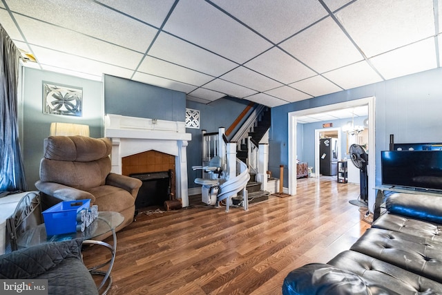 living room with a drop ceiling, wood-type flooring, and a chandelier