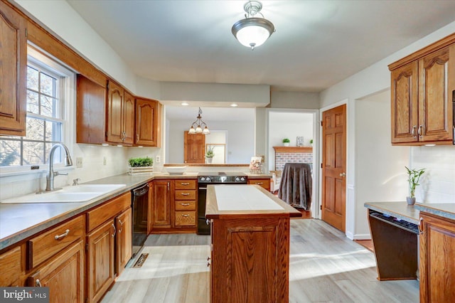 kitchen with a center island, sink, tasteful backsplash, black appliances, and light wood-type flooring